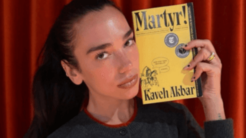 Dua Lipa holds University of Iowa professor Kaveh Akbar's book, Martyr!.